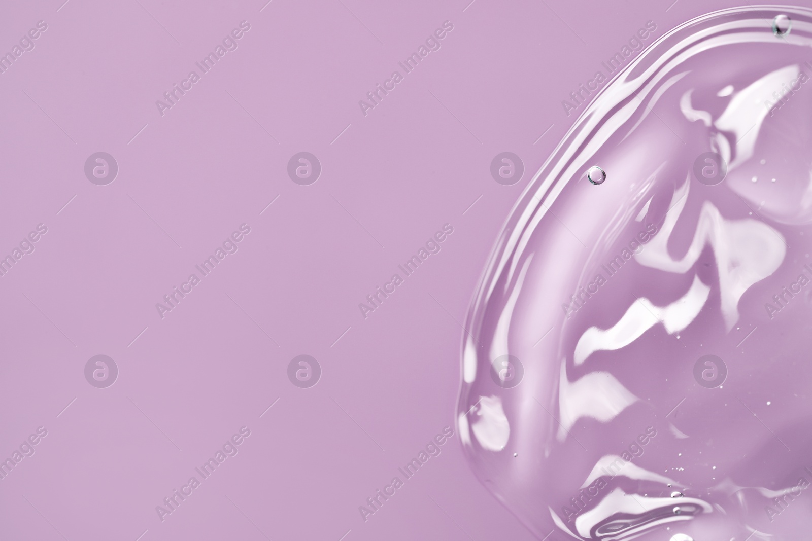 Photo of Transparent cleansing gel on violet background, top view with space for text. Cosmetic product