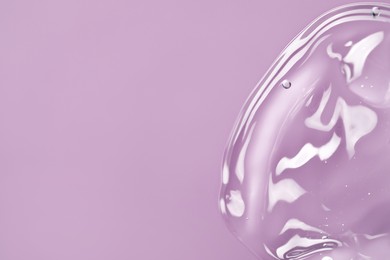 Photo of Transparent cleansing gel on violet background, top view with space for text. Cosmetic product