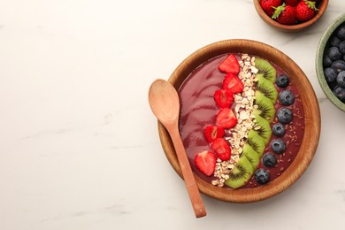 Bowl of delicious smoothie with fresh blueberries, strawberries, kiwi slices and oatmeal on white marble table, flat lay. Space for text