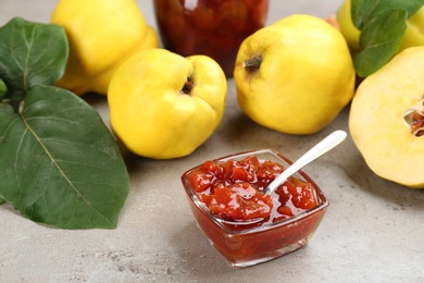 Photo of Delicious quince jam and fruits on light grey table