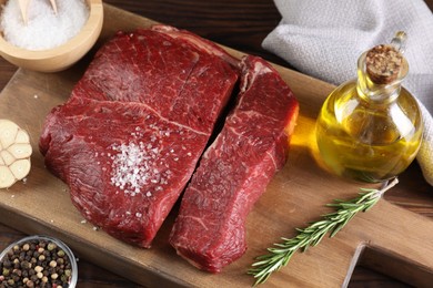 Photo of Fresh raw beef cuts with oil and spices on table, above view