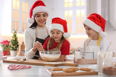 Mother with her cute little children making Christmas cookies in kitchen