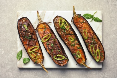 Board with fried eggplant slices on grey background, top view