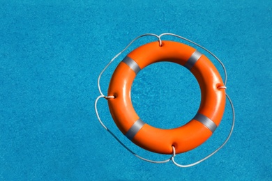 Photo of Bright orange inflatable ring floating in swimming pool, top view