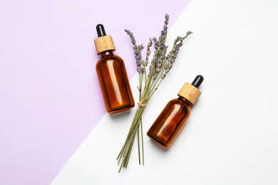 Photo of Bottles of face serum and beautiful flowers on color background, flat lay