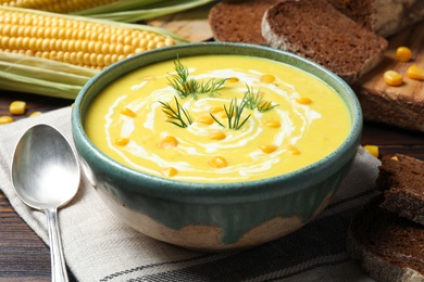 Photo of Delicious creamy corn soup served on wooden table