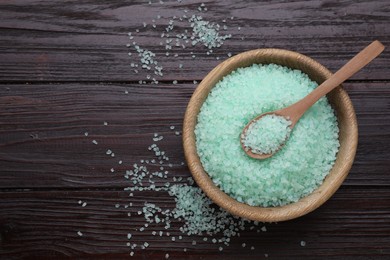 Photo of Bowl and spoon with turquoise sea salt on dark wooden table, top view. Space for text