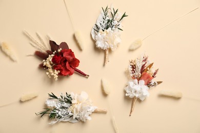 Photo of Stylish boutonnieres on beige background, flat lay