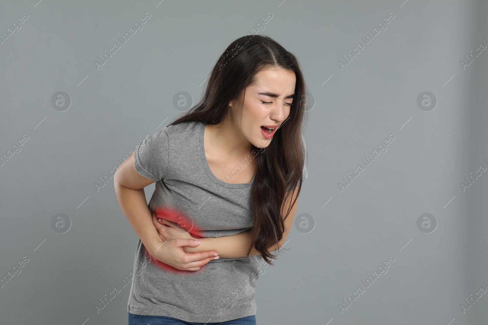 Photo of Young woman suffering from liver pain on grey background