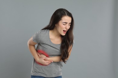 Photo of Young woman suffering from liver pain on grey background