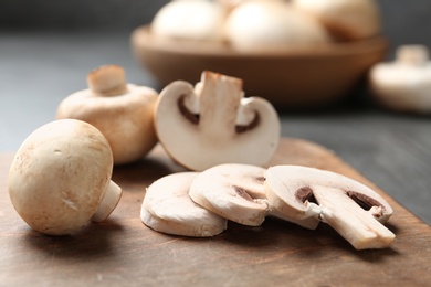 Photo of Sliced fresh champignon mushrooms on wooden cutting board, closeup