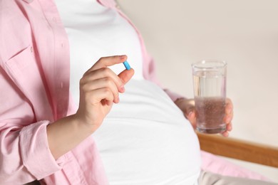 Photo of Pregnant woman taking pill in armchair, closeup. Space for text