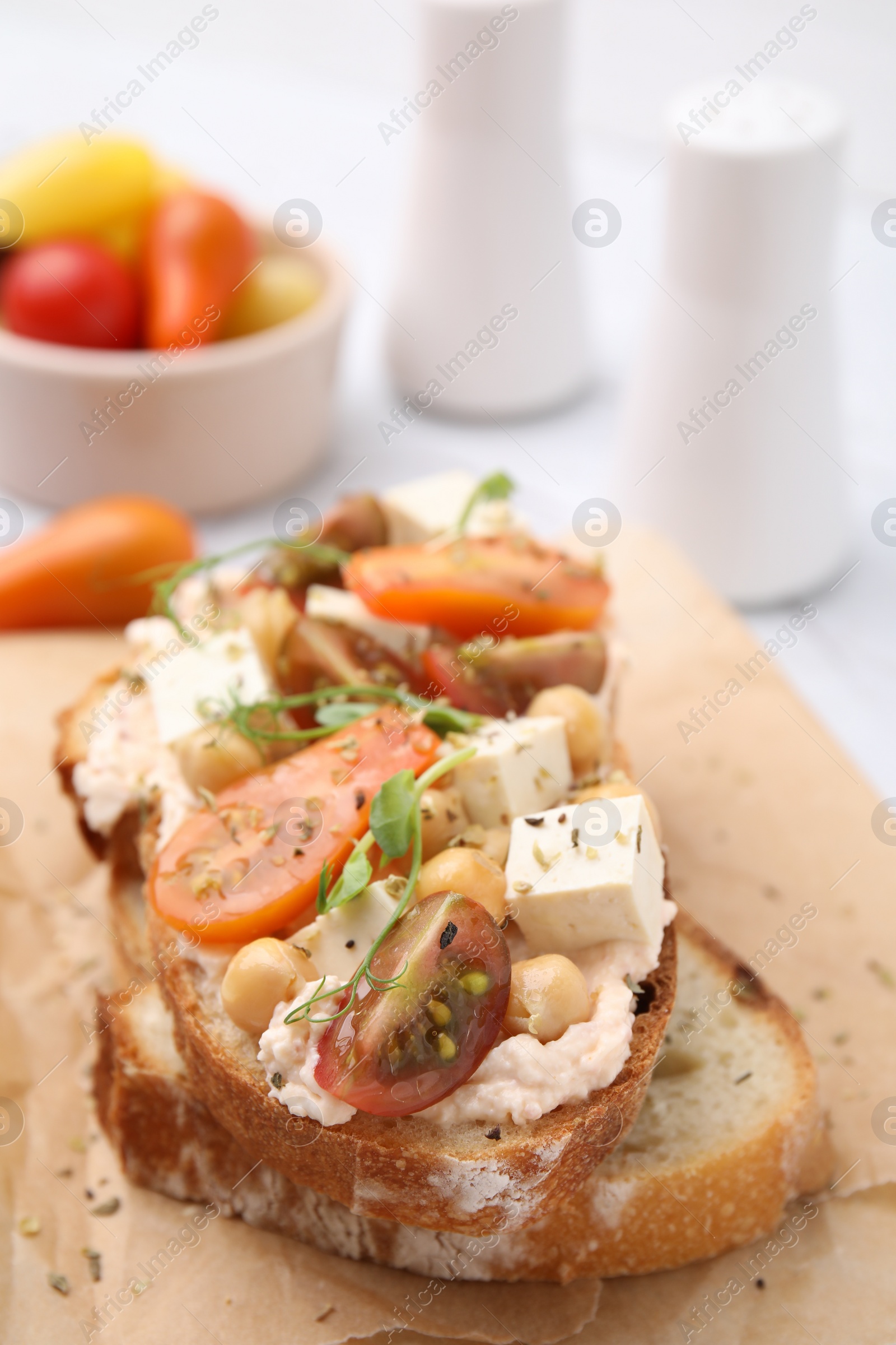 Photo of Tasty vegan sandwich with tomatoes, tofu and chickpeas on table, closeup