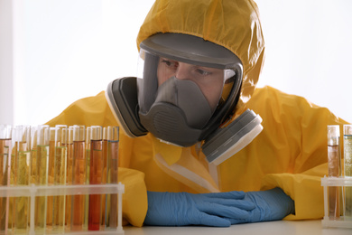 Photo of Scientist in chemical protective suit working with test tubes at table. Virus research