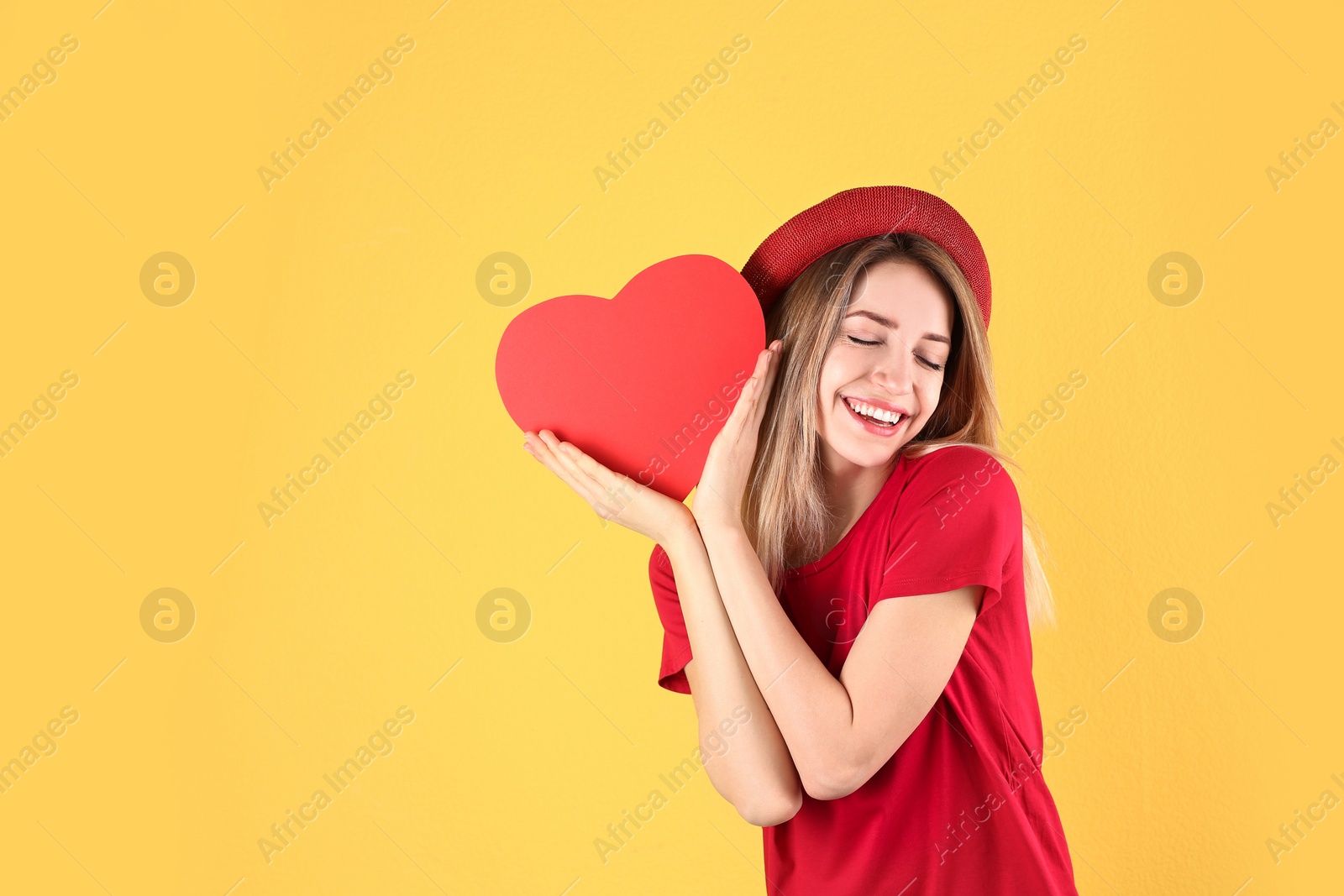 Photo of Portrait of woman with paper heart on color background. Space for text