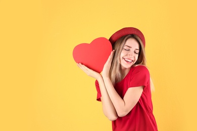 Portrait of woman with paper heart on color background. Space for text