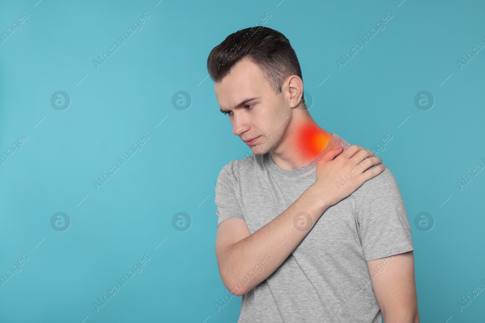 Image of Arthritis symptoms. Young man suffering from pain in his neck on light blue background, space for text