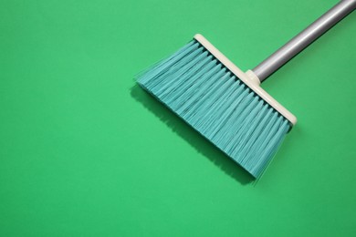 Plastic broom on green background, top view. Space for text