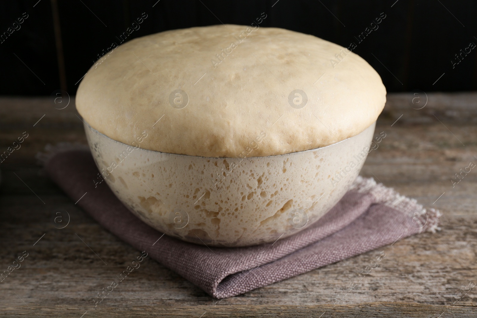 Photo of Bowl of fresh yeast dough on wooden table