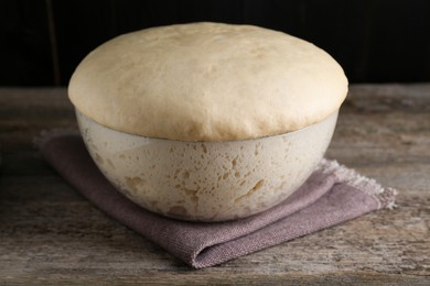 Photo of Bowl of fresh yeast dough on wooden table