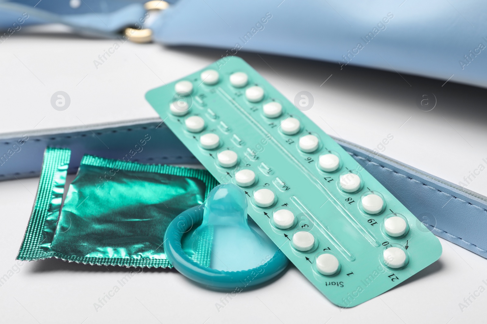 Photo of Condom and birth control pills at bag handle on white background, closeup. Safe sex concept