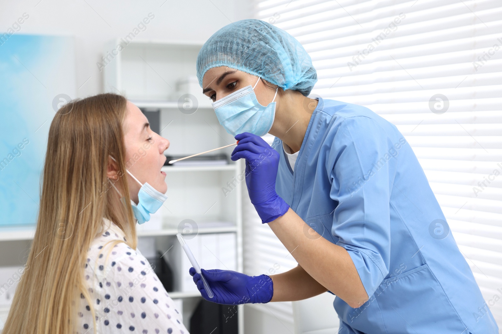 Photo of Laboratory testing. Doctor taking sample from patient's mouth with cotton swab in hospital