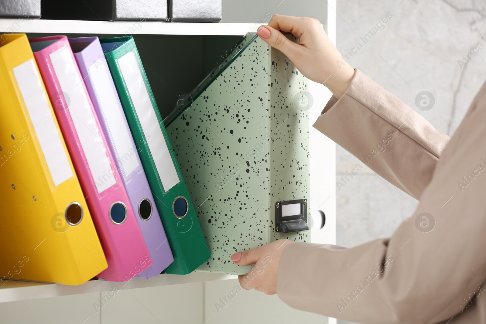 Photo of Woman taking folder from shelf in office, closeup