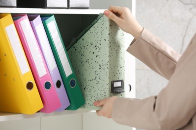 Photo of Woman taking folder from shelf in office, closeup