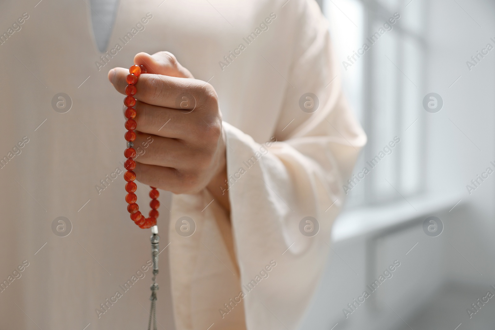 Photo of Muslim man with misbaha indoors, closeup. Space for text