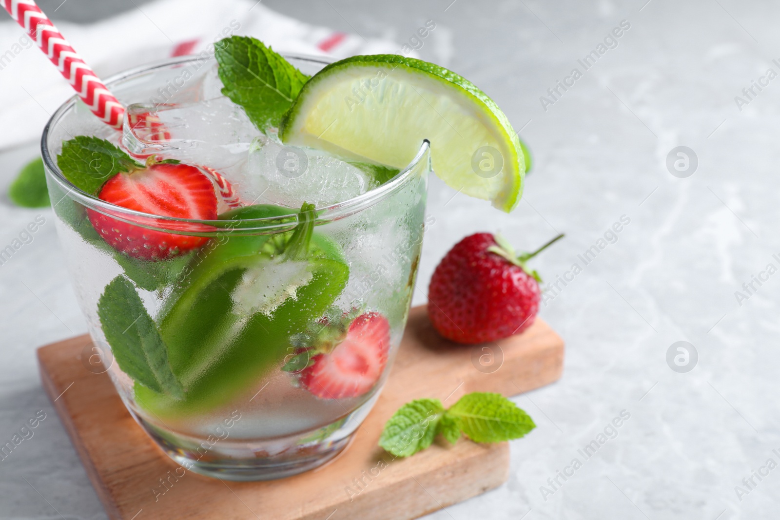 Photo of Spicy cocktail with jalapeno, strawberry, lime and mint on light grey table. Space for text