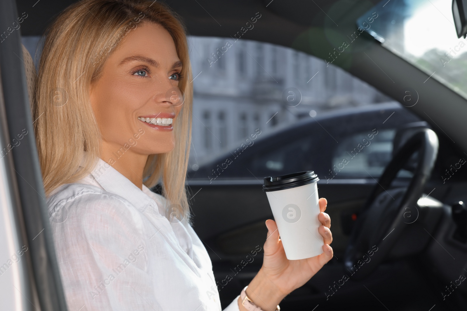 Photo of Coffee to go. Happy woman with paper cup of drink in car