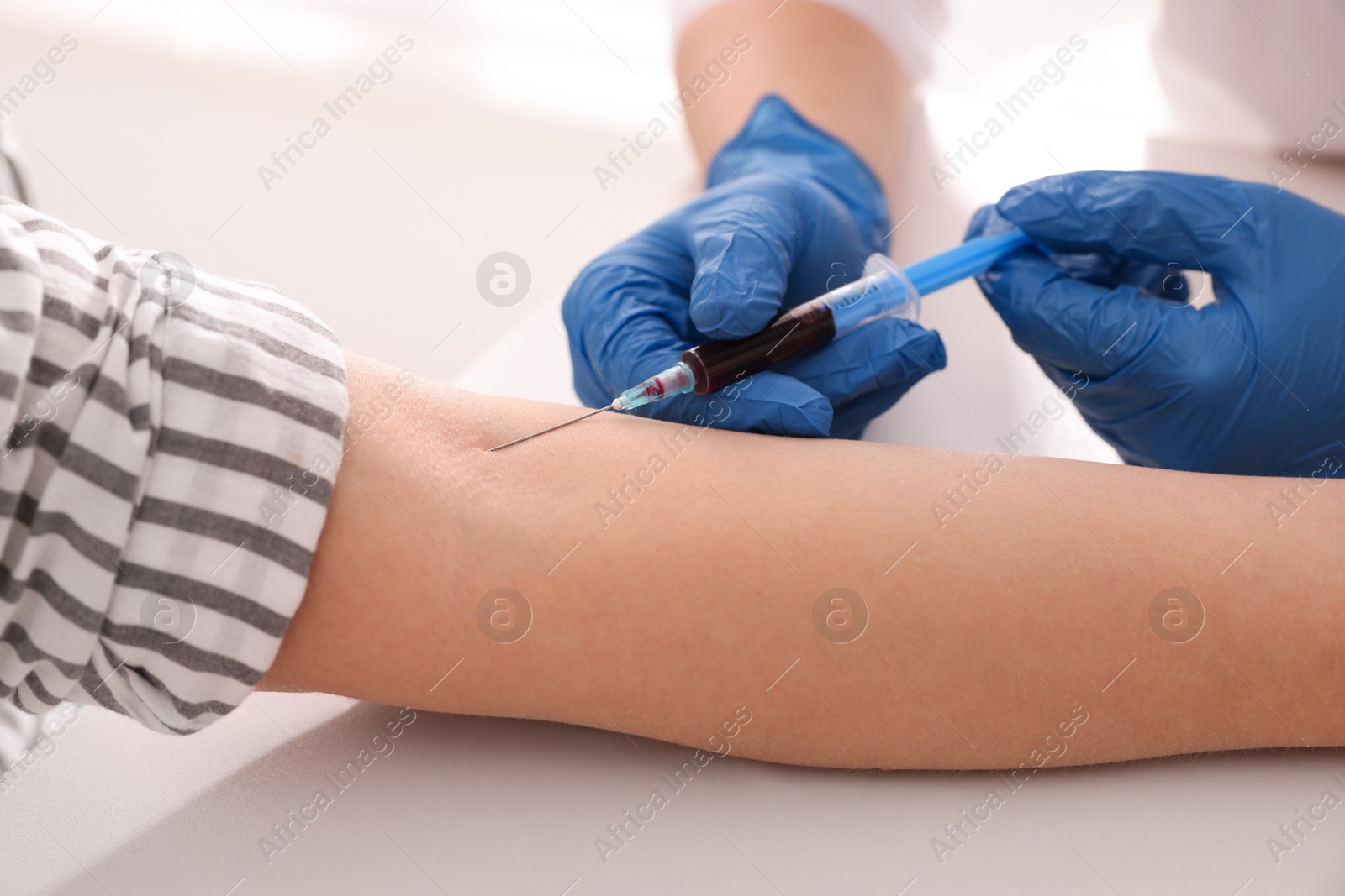 Photo of Doctor drawing blood sample of patient with syringe in hospital, closeup