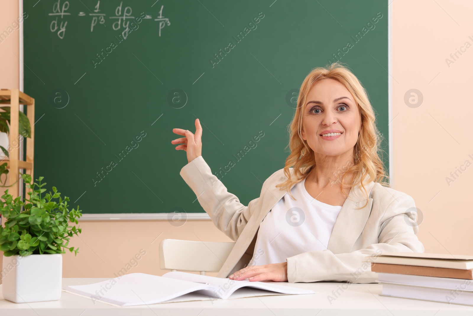 Photo of Professor pointing at green board with math equation in classroom