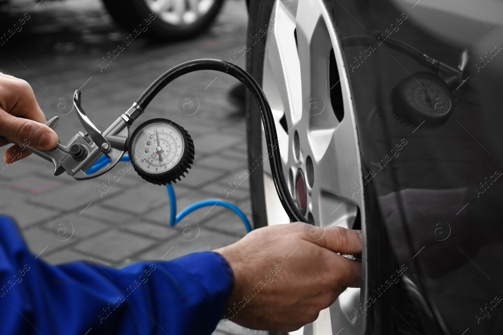 Photo of Mechanic checking tire air pressure at car service, closeup