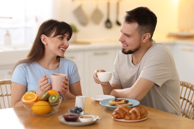 Happy couple having tasty breakfast at home