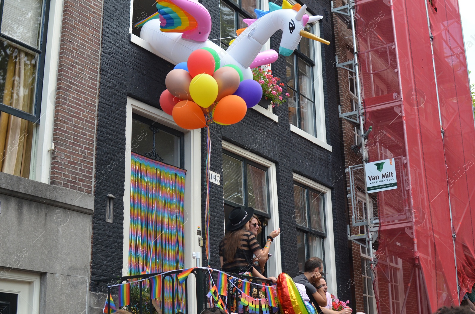Photo of AMSTERDAM, NETHERLANDS - AUGUST 06, 2022: People near building at LGBT pride parade on sunny day