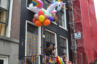AMSTERDAM, NETHERLANDS - AUGUST 06, 2022: People near building at LGBT pride parade on sunny day