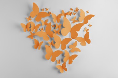 Image of Heart made of orange paper butterflies on white wall