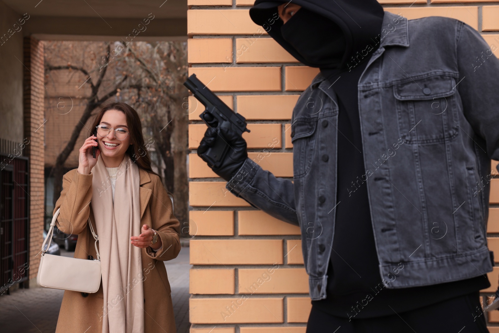 Photo of Criminal with gun hiding behind wall and waiting for victim near alley