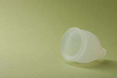 Menstrual cup on green background, closeup. Space for text