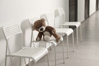 Photo of Cute lonely teddy bear on chair indoors. Space for text