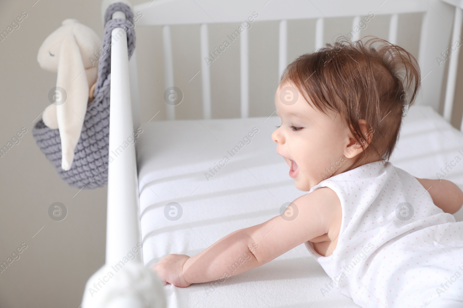 Photo of Cute little baby lying in comfortable crib at home, space for text