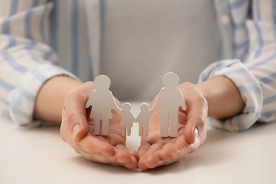 Woman holding figure of family at white table, closeup