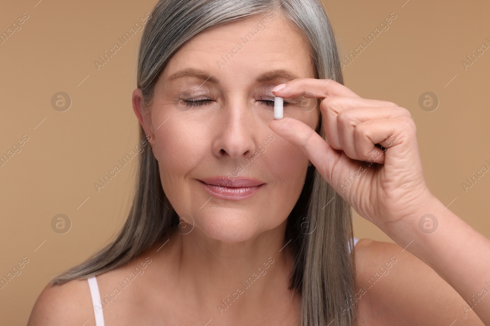 Photo of Beautiful woman with vitamin capsule on beige background