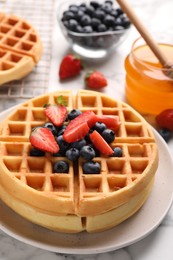 Photo of Tasty Belgian waffles with fresh berries and honey on table, closeup