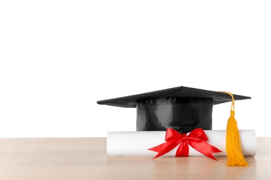 Photo of Graduation hat and diploma on table against white background