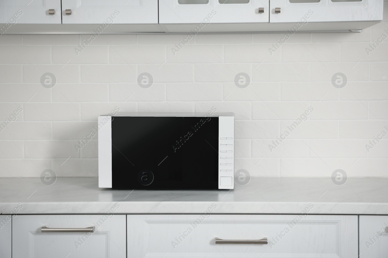 Photo of Modern microwave oven on countertop in kitchen