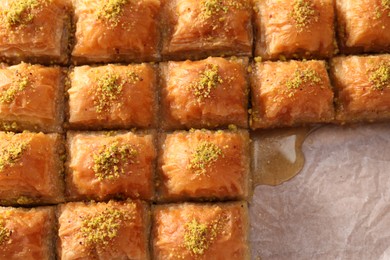 Photo of Delicious sweet baklava with pistachios on parchment paper, top view