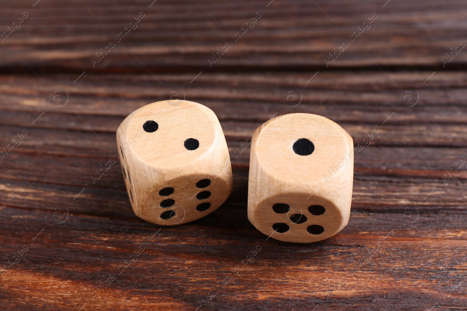 Photo of Two game dices on wooden table, closeup