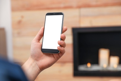 Photo of Man holding smartphone with blank screen indoors, closeup of hand. Space for text